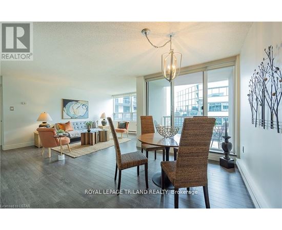 A well-lit living room with a large window and a dining table set with chairs.
