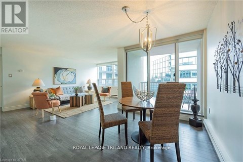 A well-lit living room with a large window and a dining table set with chairs.