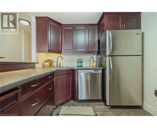 A kitchen with wooden cabinets and a stainless steel refrigerator.