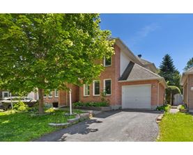 A house with a driveway and a tree in front.
