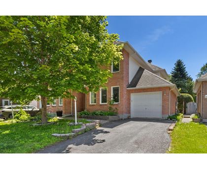 A house with a driveway and a tree in front.