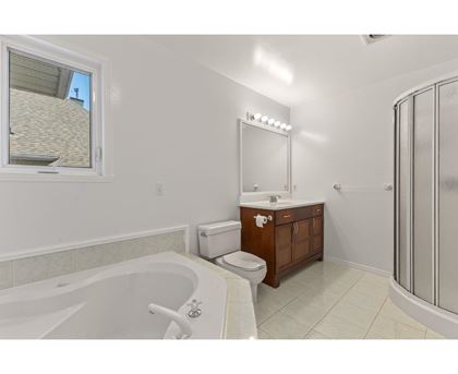 A white bathroom with a tub, toilet, sink, and mirror.