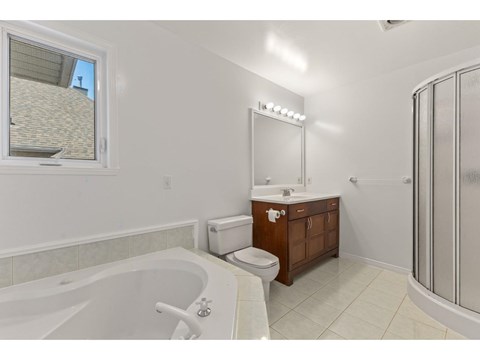 A white bathroom with a tub, toilet, sink, and mirror.