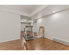 A room with a wooden floor and a white wall with a ladder and a wooden plank leaning against the wall.