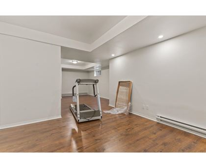 A room with a wooden floor and a white wall with a ladder and a wooden plank leaning against the wall.