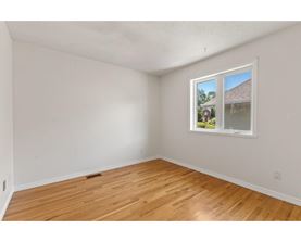 A room with a window showing a house and trees outside.