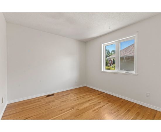 A room with a window showing a house and trees outside.