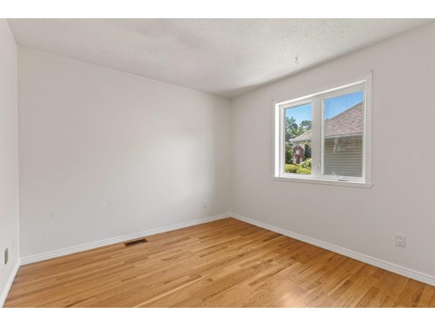 A room with a window showing a house and trees outside.