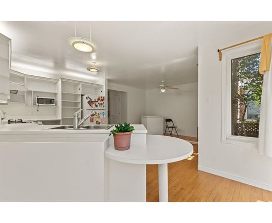 A small white kitchen with a table and a potted plant on it.