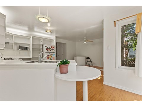 A small white kitchen with a table and a potted plant on it.
