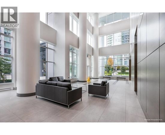 A modern living room with a black sofa and a grey armchair.