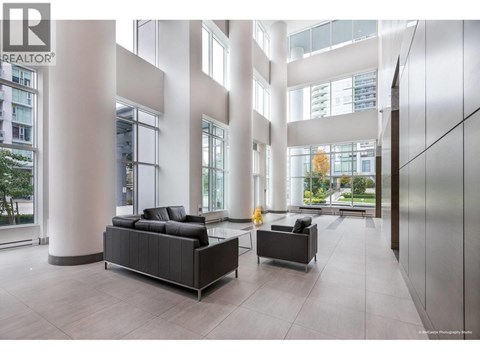A modern living room with a black sofa and a grey armchair.