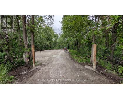 A dirt road with a sign that says "Keller Williams Realty Centres Brokerage" on the left side.