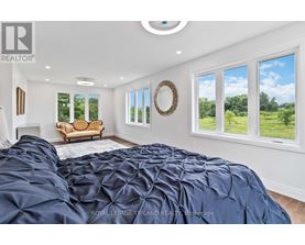 A bedroom with a large bed and a view of the outdoors through the windows.