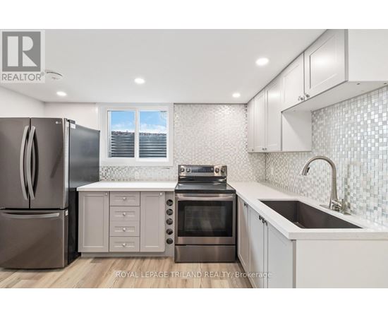 A modern kitchen with a refrigerator, oven, and sink.