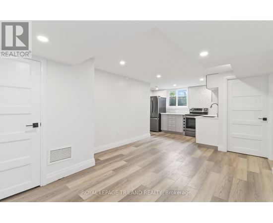 A spacious kitchen with white cabinets and a wooden floor.