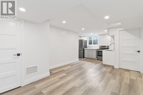 A spacious kitchen with white cabinets and a wooden floor.
