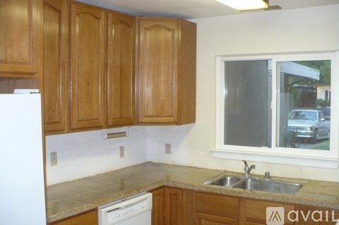 A kitchen with wooden cabinets and a white dishwasher.