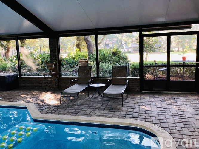 A pool with a table and chairs in front of a glass wall.