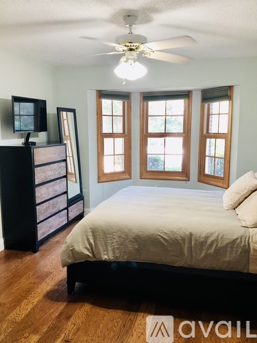 A bedroom with a bed, dresser, and a ceiling fan.