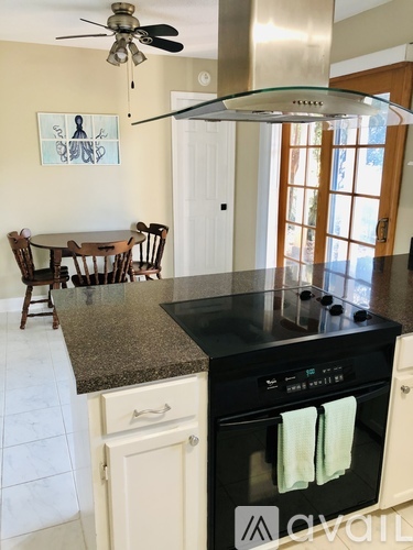 A kitchen with a black countertop and a stove with two towels hanging from it.