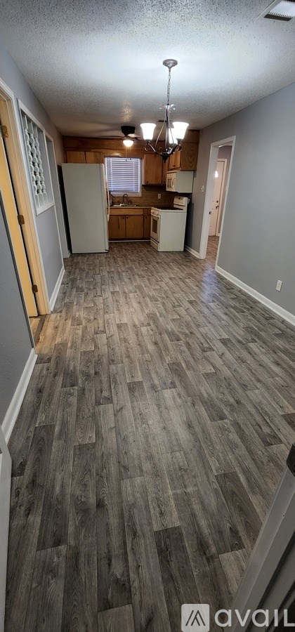 A kitchen with a refrigerator, cabinets, and a window.