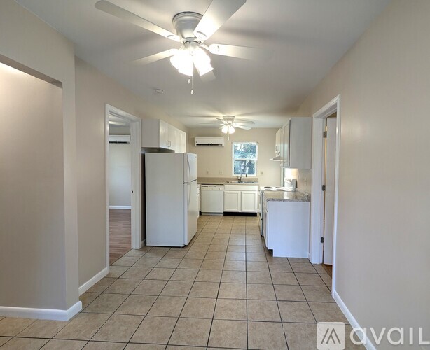 A spacious kitchen with white appliances and a tiled floor.