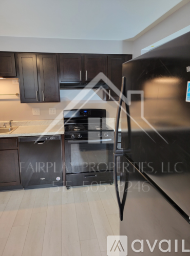 A modern kitchen with a stainless steel refrigerator and black cabinets.