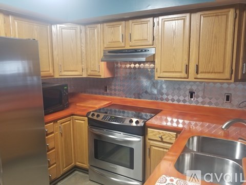 A kitchen with wooden cabinets and a stainless steel refrigerator.