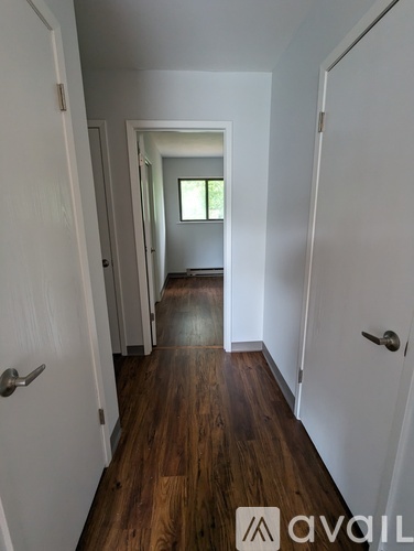 A hallway with wood floors and white walls.