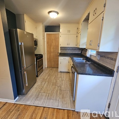 A kitchen with a black refrigerator and white cabinets.