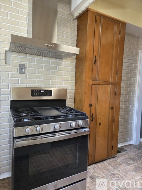 A modern kitchen with a stove and a wooden cabinet.