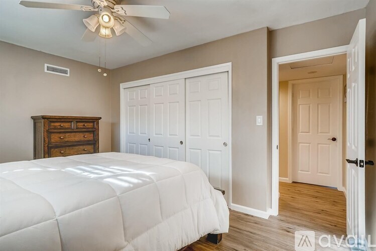 A bedroom with a white bed and a ceiling fan.