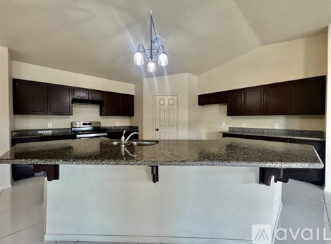 A kitchen with a granite countertop and a chandelier.
