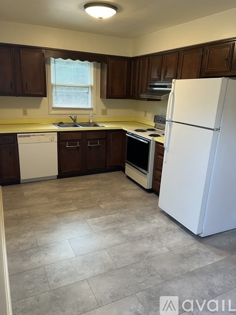 A kitchen with brown cabinets and a white refrigerator.