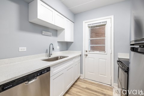 A kitchen with white cabinets and a black dishwasher.