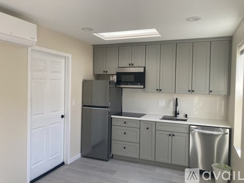 A kitchen with a refrigerator, microwave, and cabinets.