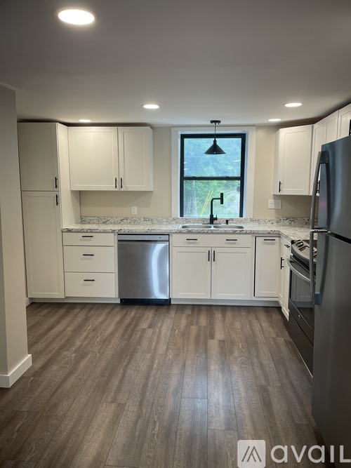 A kitchen with white cabinets and a wooden floor.