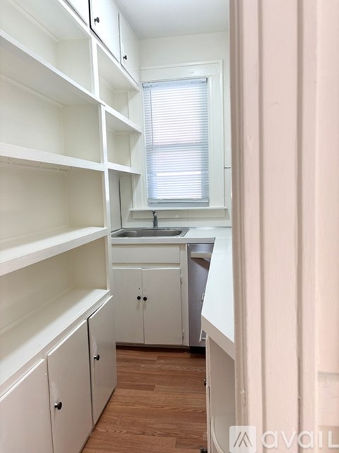 A kitchen with white cabinets and a window.