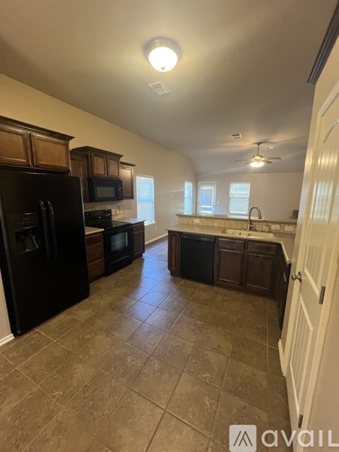 A kitchen with black appliances and wooden cabinets.
