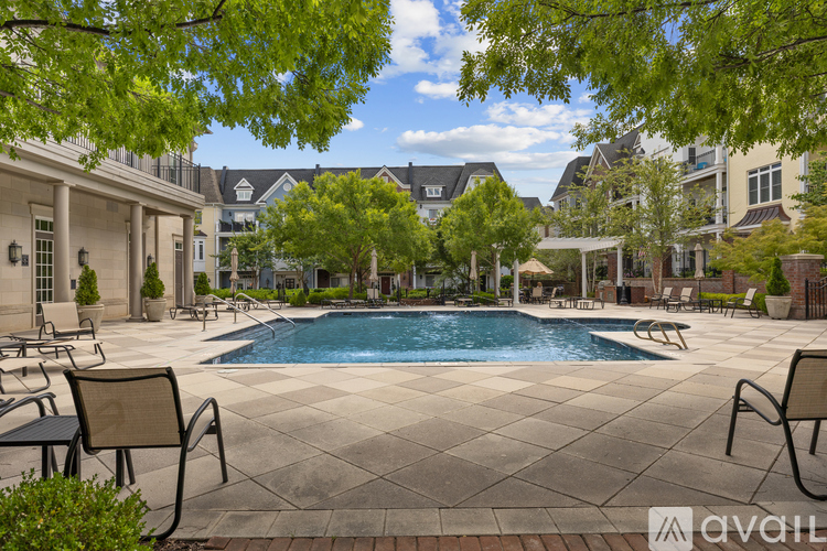 A pool surrounded by chairs and trees in a residential area.