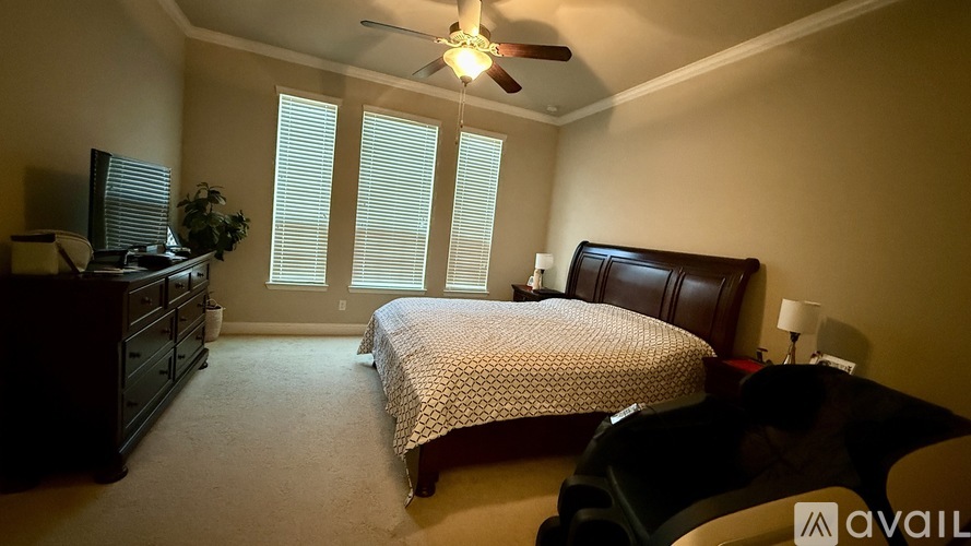 A bedroom with a bed, dresser, and ceiling fan.