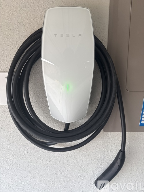 A Tesla wall charger plugged into an outlet.