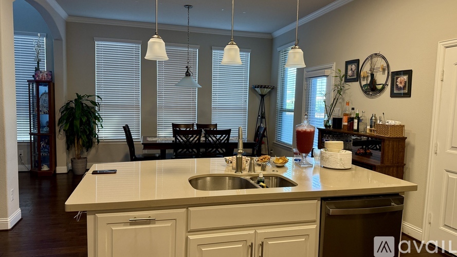 A kitchen with a sink and a counter with a glass of juice on it.