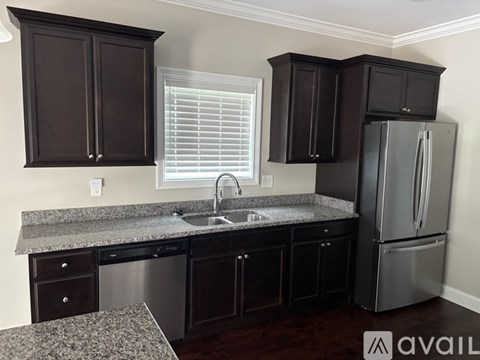 A kitchen with dark brown cabinets and a granite countertop.