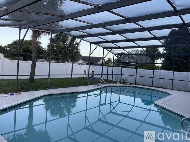 A pool under a white canopy with a palm tree in the background.