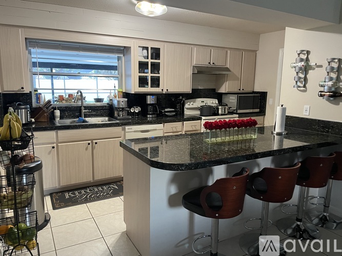 A kitchen with a black granite countertop and white cabinets.