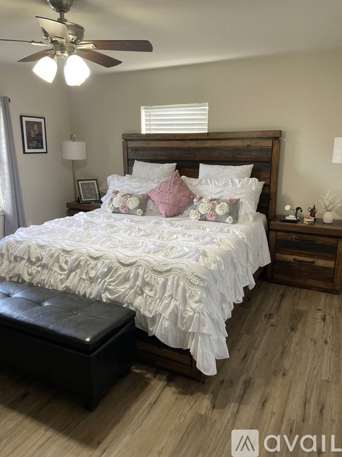 A bedroom with a large bed and a ceiling fan.