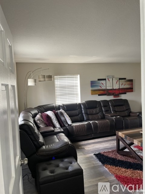 A living room with a grey leather sofa and a black ottoman.