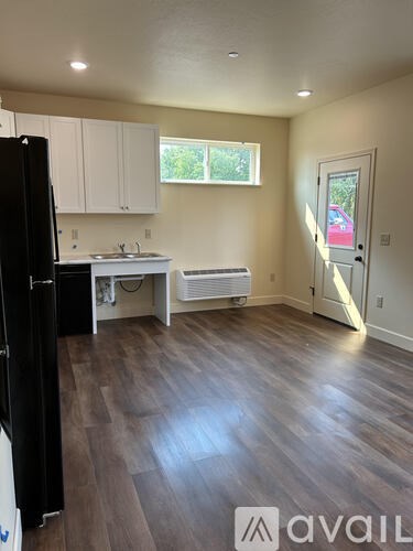 A kitchen with a black refrigerator and white cabinets.